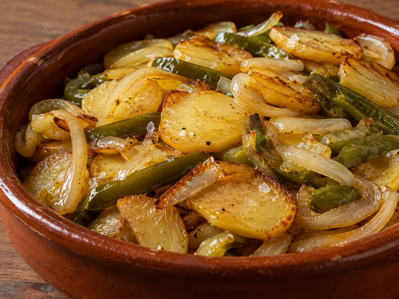 Patatas a lo pobre con cebolla y pimiento en una cazuela de barro